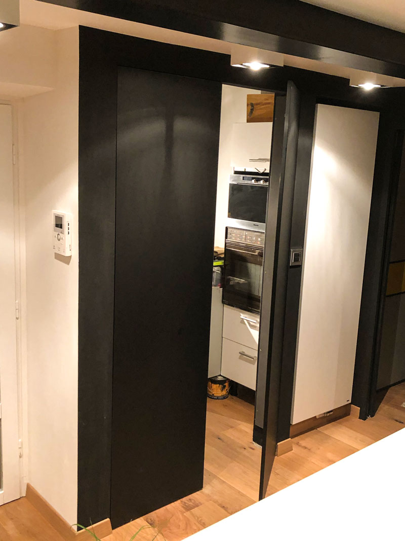Cuisine résolument moderne avec cette porte de placard qui cache en fait une arrière cuisine / cellier