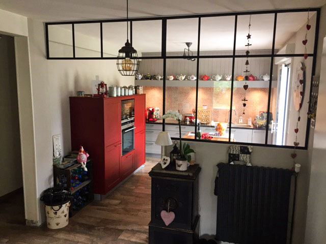 Cette cuisine d'un style très classique avec ses poignées et ses portes chanfreinées, trouve son originalité dans son meuble rouge