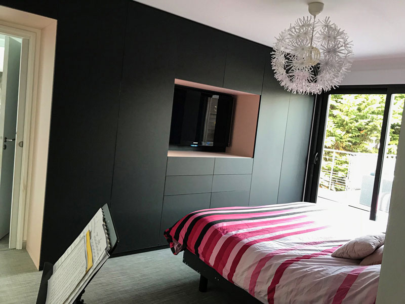 Aménagement de chambre avec placard encastré en Phœnix noir mate de chaque côté du lit. Côté opposé magnifique dressing sur-mesure avec intérieur rose pourpre