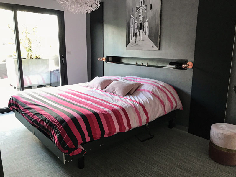 Aménagement de chambre avec placard encastré en Phœnix noir mate de chaque côté du lit. Côté opposé magnifique dressing sur-mesure avec intérieur rose pourpre
